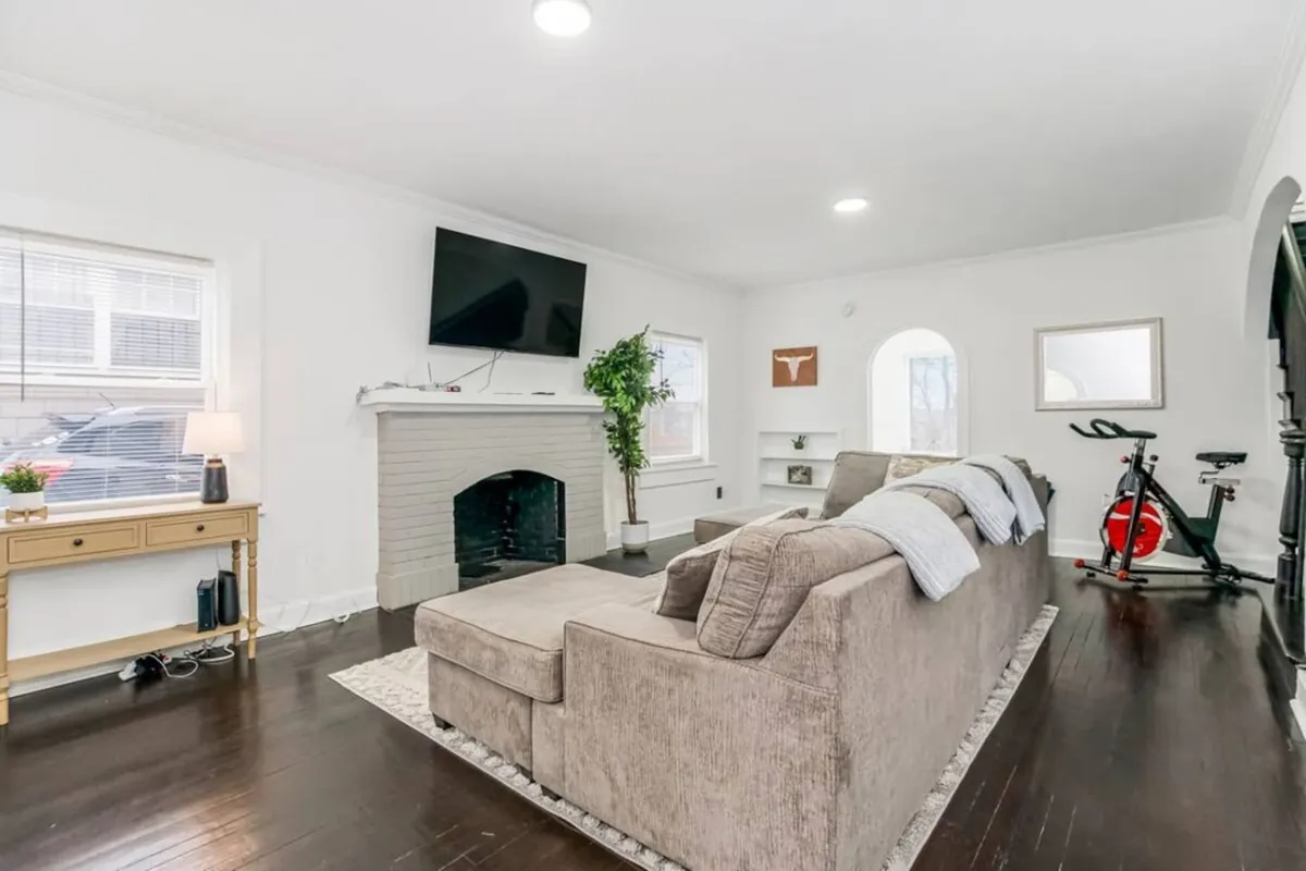This cozy living area features a sofa, fireplace, television, a plant, and an exercise bike. The space is inviting and perfect for relaxing, streaming movies, or unwinding after a night out on the town.