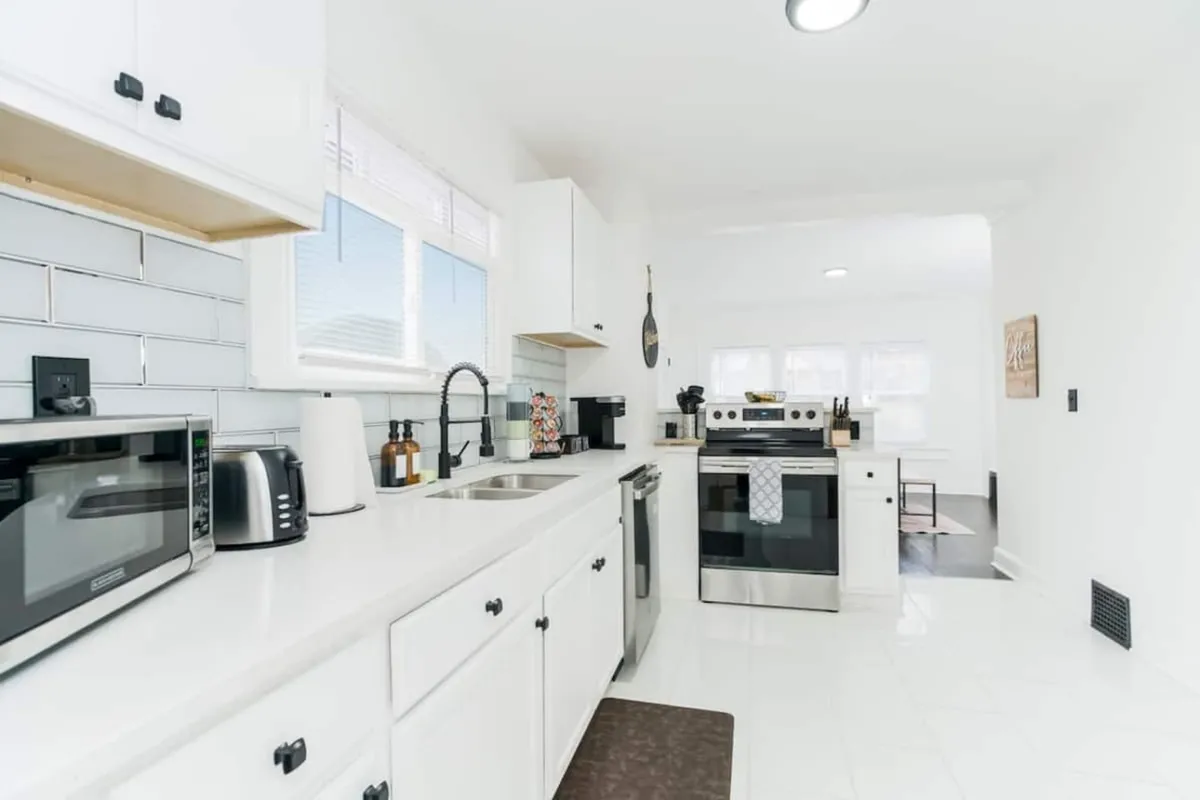 A contemporary kitchen scene with stainless steel appliances, crisp white cabinetry, a modern sink with an elegant faucet, and a kitchen island that encourages collaborative cooking and conversation. The layout is open and inviting, designed for easy movement and multiple cooks.
