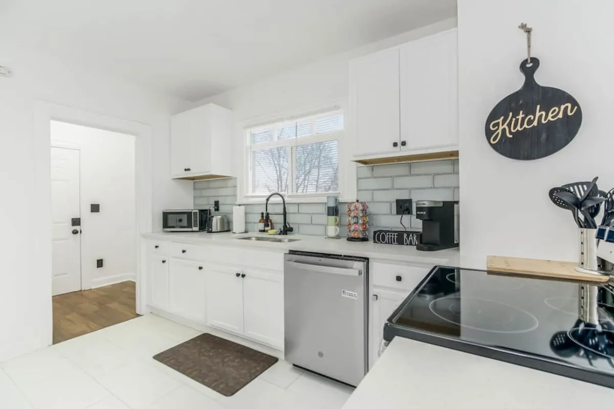 A modern kitchen with sleek cabinetry and stainless steel appliances is showcased, accompanied by a quaint coffee bar sign. The layout is perfect for cooking, socializing, and entertaining family or friends after a busy day.