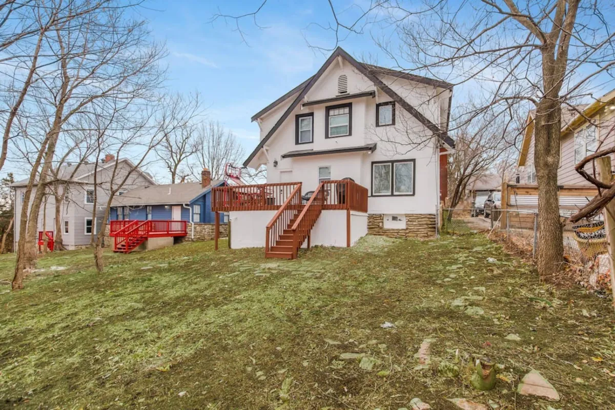 This exterior image features a spacious back deck bordered by the home's exterior walls and surrounded by mature trees. The setting is ideal for outdoor family activities, offering ample room for gatherings, barbecues, and relaxation against a backdrop of nature.